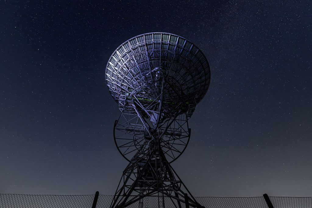eerie scenery of a radio telescope on a starry night